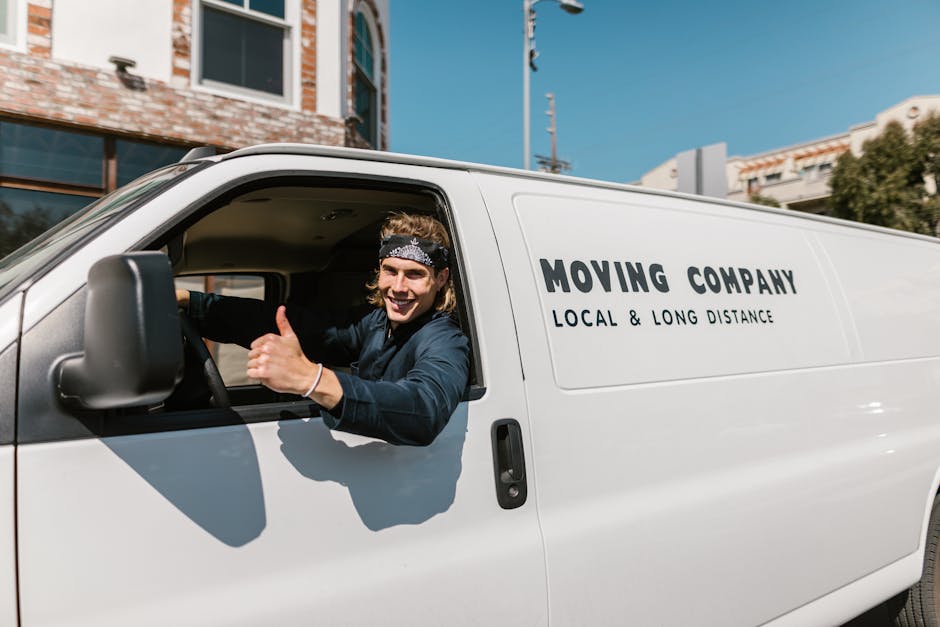A man with dark, curly hair and a beard, wearing a red long-sleeve shirt, is holding a cardboard box labeled 'OFFICE' with a recycling symbol on the corner. Next to him, a woman with curly, shoulder-l